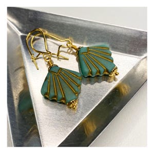 May include: A pair of gold earrings with teal blue fan-shaped glass beads. The beads have a gold-toned pattern.