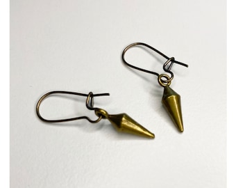 May include: A pair of gold-toned earrings with a pointed, geometric design. The earrings are made of metal and have a simple, minimalist style.