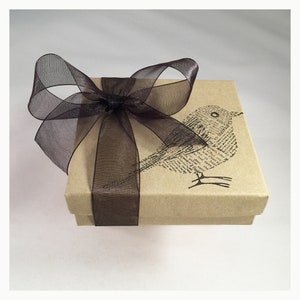 May include: A brown gift box with a black ribbon and bow. The box has a bird design printed on it.