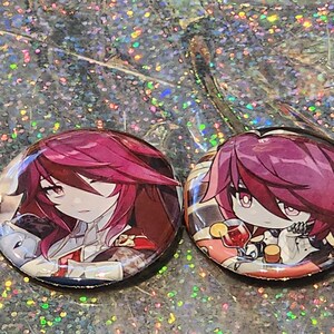 May include: Two round, glossy buttons featuring anime-style illustrations of a character with burgundy hair. One button shows the character in a detailed portrait, the other in a chibi style, holding a drink. The buttons are set against a sparkly background.