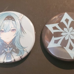 May include: Two round button pins. One features a blue-haired anime character with a black and white outfit. The other pin has a black background with a white snowflake design.