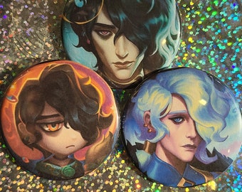May include: Three round pinback buttons featuring stylized portraits of characters with dark hair, blue hair, and light blue hair. The buttons have a glossy finish and are set against a sparkly, iridescent background.