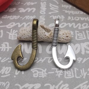 May include: Two metal fishing hook charms, one in antique gold and one in silver. The hooks are detailed with a twisted rope design and have a loop at the top for attaching to jewellery or other crafts.