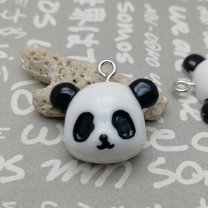 May include: Two white panda bear charms with black eyes, noses, and ears. The charms have silver jump rings for attaching to jewelry or other crafts.