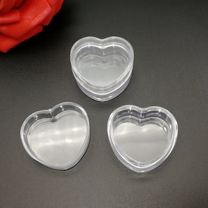Op de afbeelding: Drie transparante, hartvormige containers van plastic. De containers zijn op elkaar gestapeld.