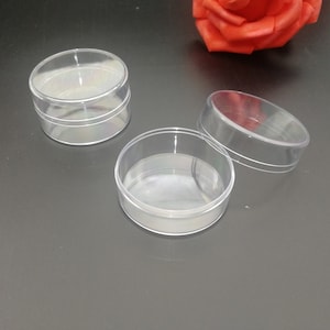 Op de afbeelding: Drie transparante plastic containers met deksels. De containers zijn rond en hebben een gladde, glanzende afwerking.