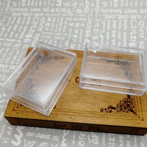 Puede incluir: Dos cajas rectangulares de plástico transparente con tapas. Las cajas están vacías y están sobre una superficie de madera.