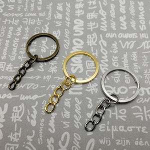 May include: Three key rings with attached chains. The key rings are made of metal and are in gold, silver, and bronze colors. The chains are also made of metal and are in gold, silver, and bronze colors.