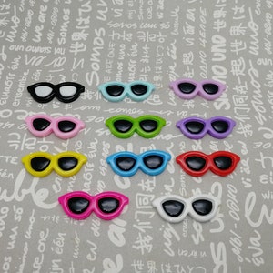 May include: Assortment of ten pairs of colorful plastic sunglasses with black lenses. The sunglasses are arranged in two rows of five.