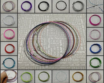 May include: A collection of 20 different colored metal chain necklaces. The chains are all the same length and are arranged in a circle. The chains are made of a variety of metals, including silver, gold, and copper.