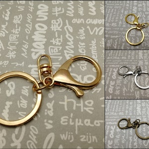 May include: Three keychains with a gold, silver, and bronze finish. Each keychain has a round ring and a lobster claw clasp.