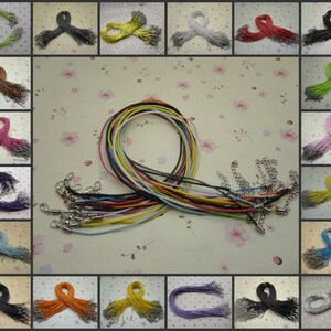 May include: A collection of colorful necklace cords with silver-tone clasps and chain extenders. The cords are in various colors, including green, yellow, red, and blue. The image is a grid of the cords.