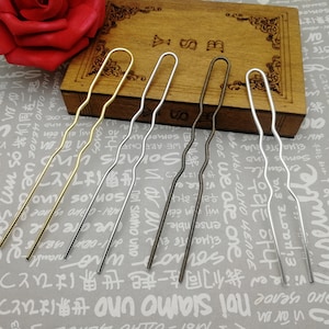 May include: Four hair pins in different colors: gold, silver, bronze, and silver. The pins are wavy and have a loop at the top.