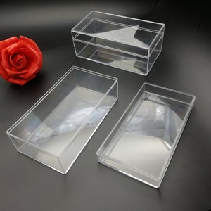 May include: Three clear plastic rectangular boxes of varying sizes. The boxes are empty and have a slight sheen.