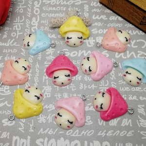 May include: Assortment of colourful mushroom-shaped charms with closed eyes and a smiling mouth. Each charm has a small loop for attaching to jewellery or other crafts.