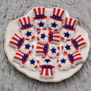 May include: A collection of 14 red, white, and blue gnome-shaped silicone charms with a star and a hat design.