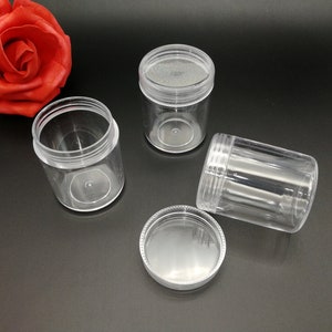 Puede incluir: Tres frascos de plástico transparente con tapas. Los frascos son cilíndricos y tienen un acabado liso y brillante. Las tapas también son de plástico transparente y tienen un diseño de rosca.