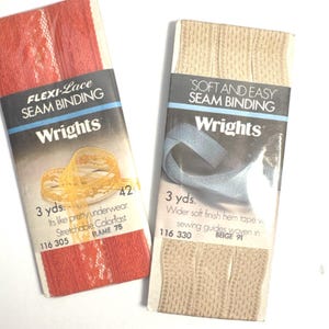Könnte beinhalten: Zwei Packungen Wrights Nahtband. Eine ist rote Spitze mit dem Text "FLEXI-Lace SEAM BINDING" und "FLAME 75". Die andere ist beige mit dem Text "SOFT AND EASY SEAM BINDING" und "BEIGE 91". Jede Packung enthält 2,74 Meter Band.