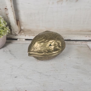 May include: A white ceramic mug with a black handle and the text "But first, coffee" in a handwritten style. The mug is on a white surface. The mug is 4 inches tall.