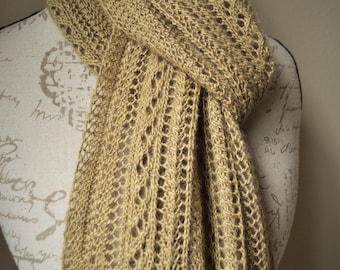 May include: A tan-colored knitted scarf with a delicate openwork design and fringe. The scarf is draped over a mannequin, showcasing its texture and intricate pattern. The scarf's length and open weave suggest it is a lightweight accessory.