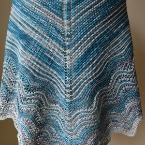 May include: A teal and gray knitted shawl with a lacy border. The shawl is made with a striped yarn and has a triangular shape.