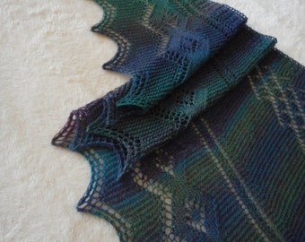May include: A teal, blue, and purple knitted shawl with a lacy pattern. The shawl is folded in half and the edges are scalloped.