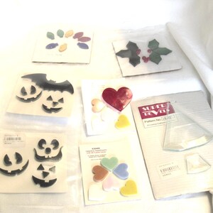 May include: Assortment of craft supplies including heart, leaf, and pumpkin-shaped embellishments. The image shows various shapes in different colors, including red, green, yellow, and black. Some items are packaged in clear plastic.