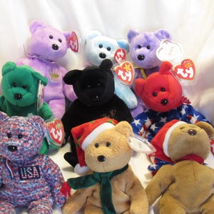 May include: A collection of colorful plush teddy bears in various colors, including green, purple, red, and black. Some bears have holiday-themed accessories like Santa hats and scarves. Each bear has a tag attached.