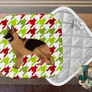 May include: A white pot holder with a red and green houndstooth pattern featuring a German Shepherd dog.