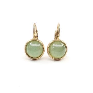 Könnte beinhalten: Ein Paar goldfarbene Ohrringe mit Klappbügel, die runde, glatte, hellgrüne Cabochon-Steine in einer einfachen Metallfassung zeigen. Die Ohrringe haben eine polierte Oberfläche und ein klassisches, kreisförmiges Design, das die Farbe betont.