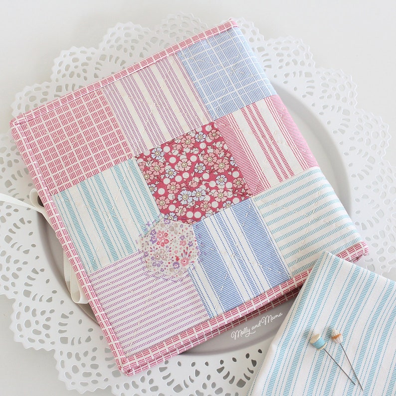 May include: A patchwork fabric book cover with a pink, blue, and white striped pattern. The cover is made of different fabrics with floral prints. The text "Molly and Mama" is visible on the bottom right corner.