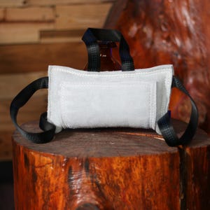 May include: A white leather dog bite sleeve with black straps. The sleeve is designed for training dogs to bite and hold.