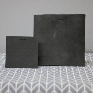 May include: Two black leather journals with the text "Leather Age" embossed on the front covers.