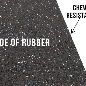 Puede incluir: Primer plano de una estera de goma negra con motas de colores. La estera est&aacute; hecha de goma y es resistente a las mordidas. "MADE OF RUBBER" y "CHEW RESISTANT" est&aacute;n impresos en la estera.