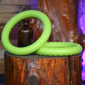 May include: Two bright green rubber dog chew rings stacked on top of each other. The rings have a textured surface and are designed for chewing.
