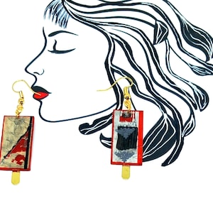 Peut inclure: Une paire de boucles d'oreilles pendantes rectangulaires rouges et dorées. Les boucles d'oreilles présentent un motif texturé abstrait dans des tons de gris, noir et blanc.