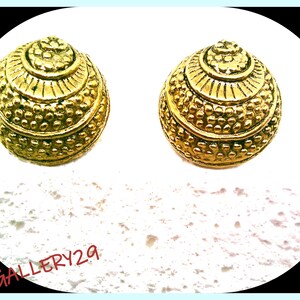 Peut inclure: Une paire de boucles d'oreilles dorées avec un design circulaire texturé. Les boucles d'oreilles ont un motif de cercle concentrique surélevé et une surface en pointillés.