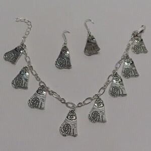 May include: A silver charm bracelet with multiple cat charms and a matching pair of cat dangle earrings.