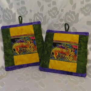 May include: Two green, yellow, and purple quilted pot holders with a colorful cheetah print design.