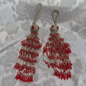May include: Two red and silver beaded tassels with a loop at the top for hanging.