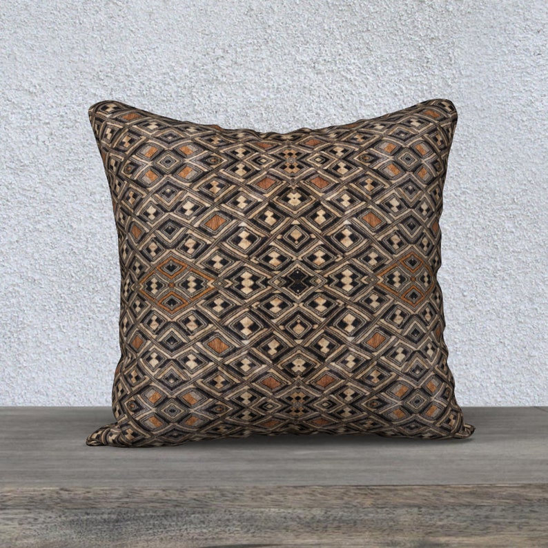 May include: A decorative throw pillow with a geometric pattern in shades of brown, black, and white. The pillow has a square shape and a soft, plush texture.