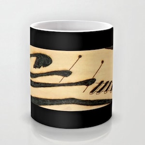Könnte beinhalten: Eine schwarze Kaffeetasse mit weißem Innenraum. Die Tasse zeigt ein Schwarzweißbild einer liegenden Person mit einem Xylophon im Hintergrund.
