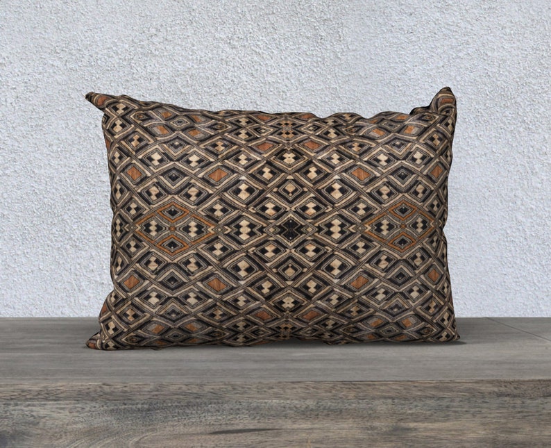 May include: A decorative throw pillow with a geometric pattern in shades of brown, black, and beige. The pillow has a diamond-shaped design with a subtle sheen.