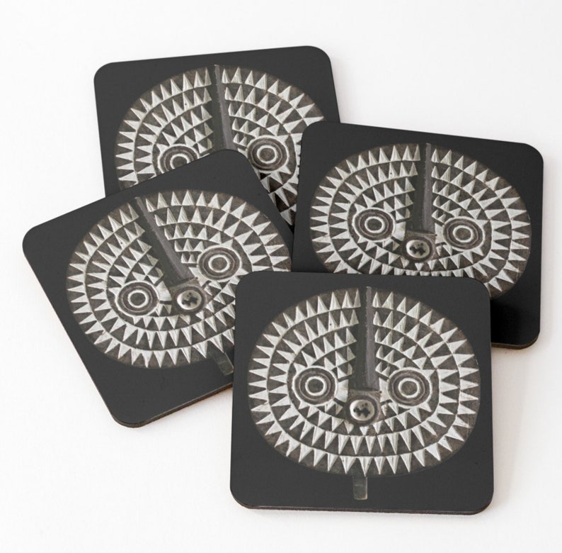 May include: Set of four black coasters with a white and gray geometric design. The design features a circular pattern with a central vertical line and two circles.
