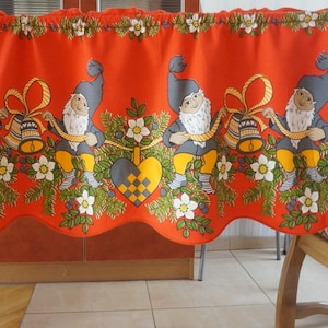 Può includere: Valance in tessuto rosso con un bordo inferiore a forma di conchiglia. La valance presenta un motivo ripetitivo di gnomi che tengono campane e un design a forma di cuore. Gli gnomi indossano cappelli blu e pantaloni gialli.