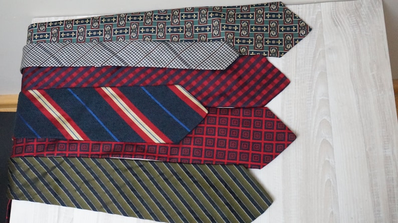 Puede incluir: Seis corbatas de diferentes patrones en una variedad de colores, incluyendo verde, gris, rojo y azul. Las corbatas est&aacute;n dispuestas en una pila, con la corbata superior siendo verde y la corbata inferior siendo verde.