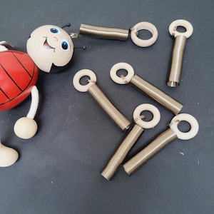 Può includere: Sei anelli di legno con molle metalliche attaccate. Gli anelli sono bianchi e le molle sono argentate.