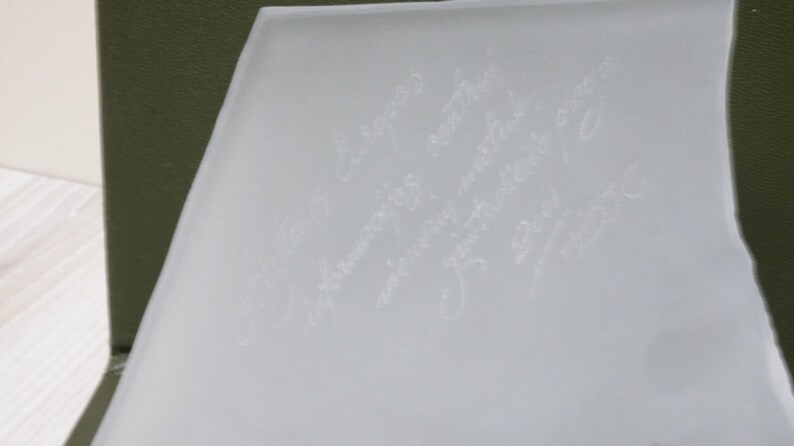 May include: A white frosted glass surface with several handwritten messages in white ink.