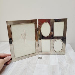 May include: Silver-toned multi-frame picture frame with five openings. The frame has a rectangular opening on the left and four openings on the right. The four openings on the right are two rectangular and two oval.