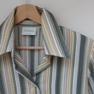 Puede incluir: Una camisa de manga larga a rayas con cuello. La camisa es verde, amarilla, blanca y roja. La camisa tiene una etiqueta que dice "DOCOO".